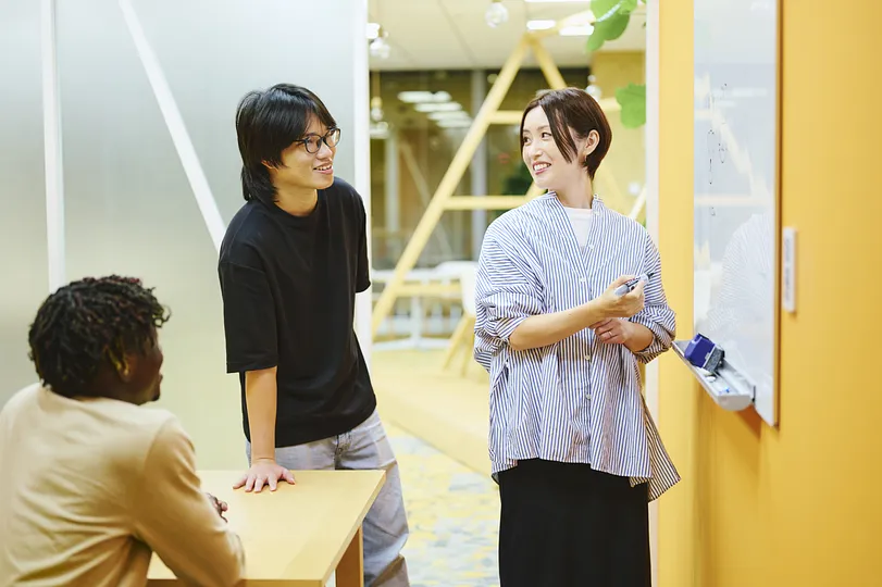 A person at a whiteboard, with two others watching