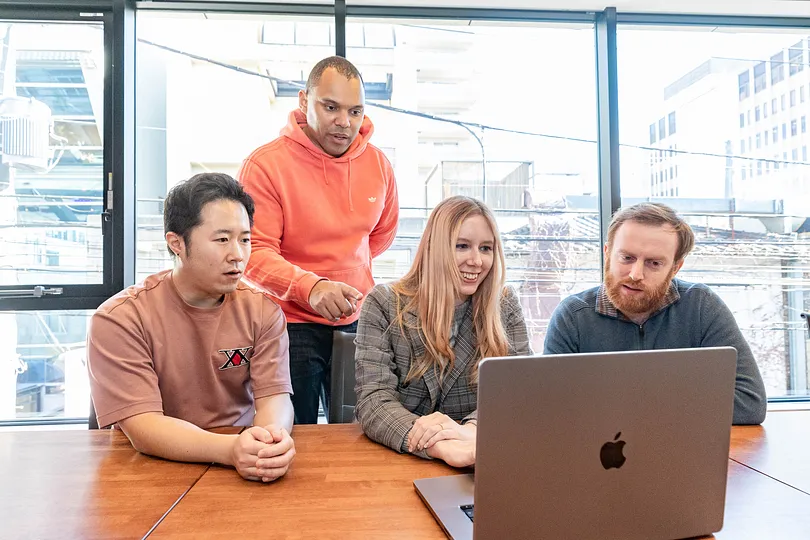Four people looking at a laptop