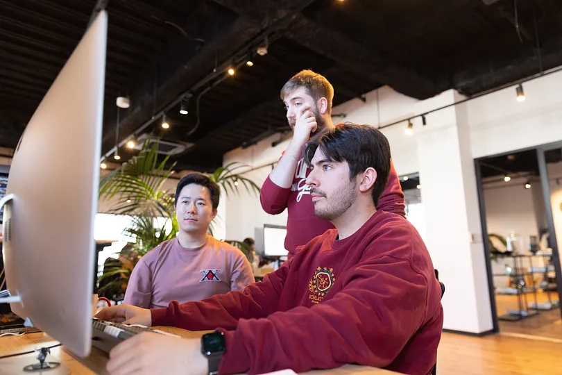 Three people looking at a monitor