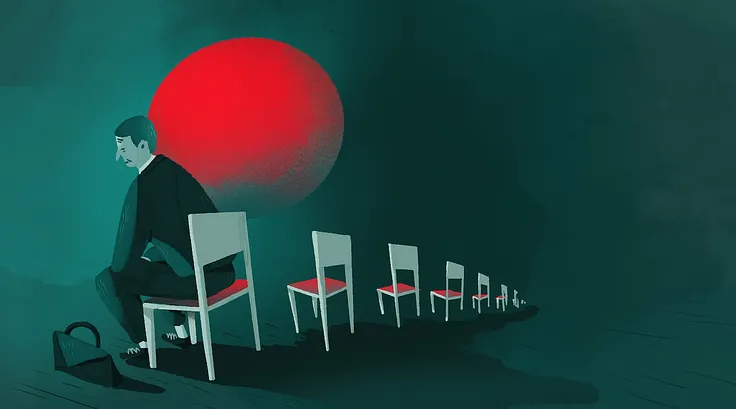 A man in a suit sitting in an empty row of chairs