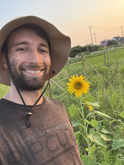 Levi next to a sunflower as the sun sets.